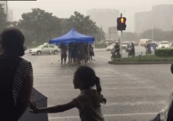 一群人在下雨天抬着遮雨棚过马路