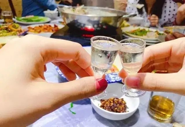 举起小酒杯碰杯的图片
