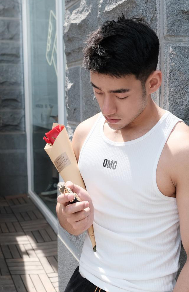 手拿一枝玫瑰花等女朋友的男生